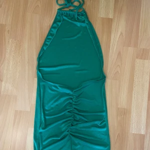 Klänning med öppen rygg  - Kort klänning med öppen rygg och ”scrunch” på rumpan. Stretchigt material. Använd en gång.