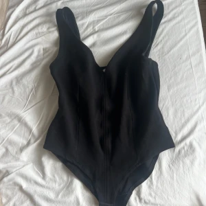 Svart body från H&M i linne. - Använd få gånger. Man knäpper bodyn längst ner där man kan välja olika längder, beroende på hur tajt man vill ha den.