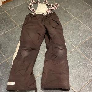 Termos ridbyxor från H&M - Bruna temos ridbyxor från H&M med hängslen och vita sidopaneler. Reflexerna är slitna, även slitet längts ner av ena byxan💕