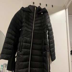 Svart dunjacka från Michael Kors - Snygg svart dunjacka från Michael Kors med huva och dragkedja. Jackan har en quiltad design och praktiska fickor. Perfekt för kyliga dagar. Jackan är inte använd och är i ny skick. ‼️ÄKTA‼️