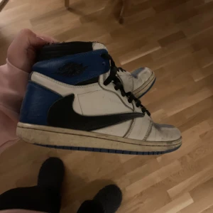 Nike Air Jordans i blått och vitt - Säljer ett par klassiska Nike Air Jordans i blått och vitt med svarta detaljer. Skorna har snörning och en hög design som ger bra stöd. Perfekta för sneaker-entusiaster!
