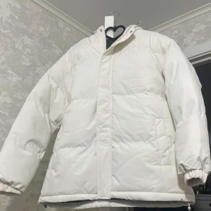 Vit pufferjacka - Säljer en helt ny stilren vit pufferjacka. Jackan har en klassisk design med två sidofickor och är perfekt för kyligare väder. Storlek L men passar även för en som har M