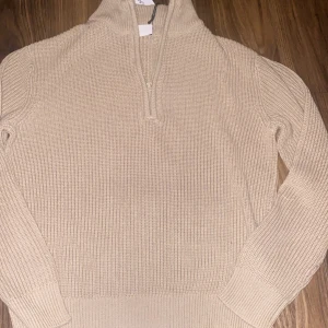 Beige stickad tröja från Grunt - Storlek L i barn, den passar dig som är runt 170, Säljer en stilren beige stickad tröja från Grunt med dragkedja vid halsen som är helt oanvänd med prislappen kvar. Perfekt för kyliga dagar med sin mjuka och bekväma passform. Hör av dig vid funderingar! Nypris runt 600-700kr 