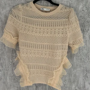 Beige spetsblus - Så fin spets topp från Zara med volanger. Ser ut som att det är en body men det är sluts på sidorna där volangerna är vilket är väldigt snyggt. Den är helt ny och aldrig använd. Saknar tyvärr prislapp men endast testad. 
