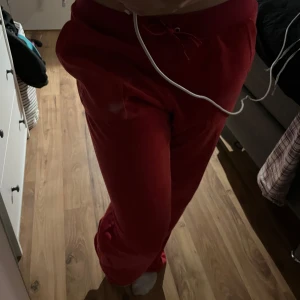 Röda mjukisbyxor från Juicy Couture - Snygga röda mjukisbyxor från Juicy Couture med snörning i midjan, där dock silver grejerna åkt av. Perfekta för en avslappnad stil och superbekväma att bära. Passar perfekt för mysiga dagar hemma eller en chill dag ute.