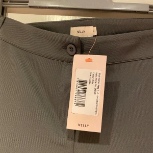 Grå kostymbyxor från Nelly - Grå Low Waist kostymbyxor från Nelly. Storlek XL. Passar L-XL beroende på hur man vill att de ska sitta. Helt nya & oanvända. Nypris 399kr. 