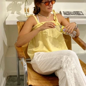 Gul ärmlös topp - Snygg gul ärmlös topp med smala axelband och volangdetaljer vid halsringningen. Perfekt för varma sommardagar och strandäventyr.