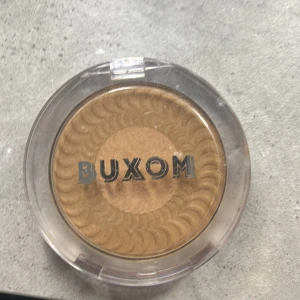 Buxom bronzer - Snygg bronzer från Buxom i en varm, gyllene nyans. Perfekt för att ge ansiktet en solkysst look. Kommer i en praktisk rund förpackning med genomskinligt lock.