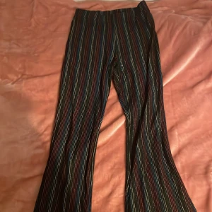 Randiga byxor med glittereffekt - Snygga byxor med färgglada ränder och en glittrig finish. Perfekta för att sticka ut med en unik stil. Passar för åldrarna 11-12 år.