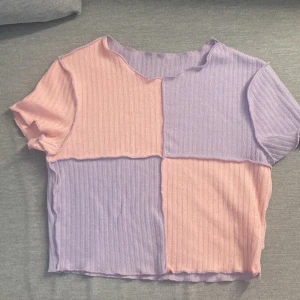 Ribbad topp i pastell från Shein - Säljer en söt ribbad topp i pastellfärger från Shein. Toppen har korta ärmar och är i en kombination av ljusrosa och ljuslila. Perfekt för en färgglad look!