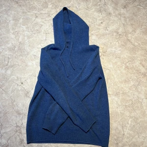 Ljusblå Kashmir/merino ull hoodie  - Säljer min snygga kashmir hoodie pga att den blivit för liten för mig. Endast en liten defekt som syns på bild 2 därav de billiga priset. Tröjan är skön och stilren och perfekt till det kalla vädret. Tröjan är storlek S.