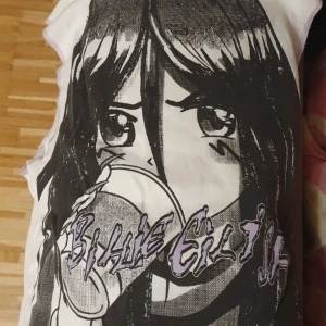 Vit t-shirt med anime-tryck - Säljer en vit t-shirt med ett stort anime-tryck i svart och texten 'Billie Eilish' i lila. Perfekt för fans av både anime och musik. T-shirten har korta ärmar och en avslappnad passform. Har bara använt den 1 gång 