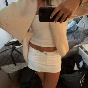 Vit kortkjol med dragkedja - Snygg Low waist vit kortkjol med dragkedja framtill. Perfekt för en stilren look. Kjolen är enkel och passar till många olika toppar. 