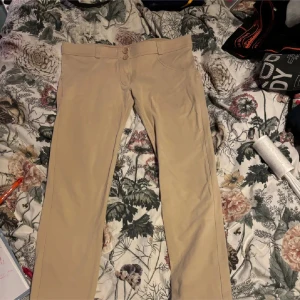 Beige byxor från WR.UP - Snygga beige byxor från WR.UP med hög midja och tight passform. Byxorna har en stilren design med två knappar i midjan och är perfekta för en chic look.