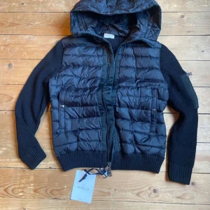 Svart cardigan från Moncler - Snygg svart cardigan från Moncler med huva. Har inte haft den särskilt länge men är sygen på en ny jacka därför säljer jag den. Jag köpte den på NK. Hör av dig vid frågor eller om du vill ha fler bilder.