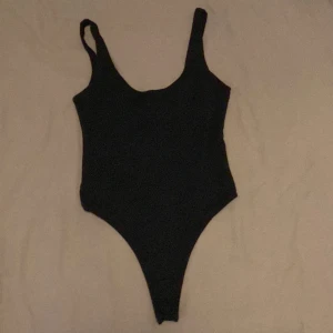 Body  - Tight svart body från Bik Bok i bomullsblandning. Ganska urringad fram och har djup ringning bak. Är sydd med dubbelt tyg och håller formen bra. Knappar i grenen