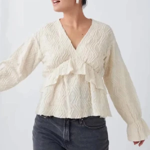 Beige blus med volangdetaljer - Snygg beige blus med v-ringning och volangdetaljer. Blusen har ett subtilt mönster och långa ärmar, perfekt för en stilren look💗💗