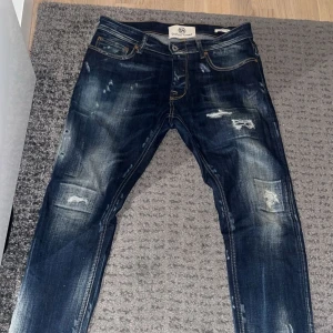 Mörkblå jeans med slitningar - Säljer ett par sjukt feta Taylor tweed jeans sitter rätt likt som dondup George modellen. Storlek 31