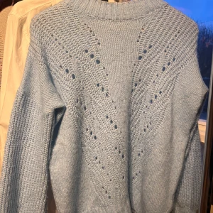 Ljusblå stickad tröja  - Superfin ljusblå stickad tröja från Madlady i storlek XS. Den har ett snyggt hålmönster framtill. Tröjan är mjuk och bekväm med långa ärmar och ribbad krage. Perfekt för både vardag och fest med en snygg topp under! 💙