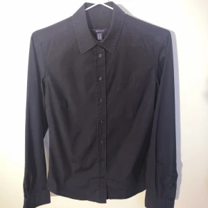 Slim fit stretch skjorta från Gant - Mörkblå slim fit stretch skjorta i bommul från GANT. Storlek 36/Small dam. Nypris 1400 kr. Köparen står för fraktkostnaden. 