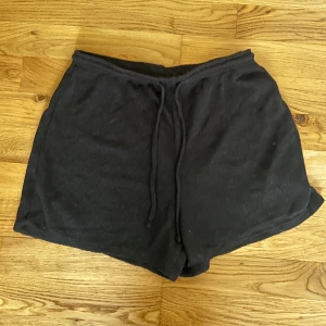 Svarta shorts från H&M - Säljer ett par svarta shorts från H&M i storlek S. De är superbekväma med en loose passform och har en praktisk dragsko i midjan. Perfekta för en avslappnad dag hemma eller en promenad i parken. 🖤