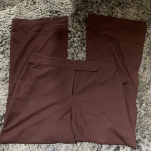 Bruna byxor från B:B - Säljer ett par bruna byxor från B:B i storlek 46. De har en enkel och stilren design med en rak passform. Perfekta för både vardag och festliga tillfällen. Materialet känns mjukt och bekvämt mot huden.