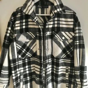 Rutig jacka från Zara - Säljer en supercool rutig jacka från Zara i svart och vit. Den har långa ärmar och knappar framtill. Perfekt trendig, varmt och mysigt och funkar både till vardags och fest. Storleken är dam S Jackan är i nyskick och redo för nya äventyr!