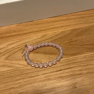 Rosa armband med pärlor - Säljer ett sött rosa armband med runda pärlor. Perfekt för att ge en romantisk touch till din outfit. Armbandet är elastiskt och passar de flesta handleder. Perfekt för både vardag och festliga tillfällen. 💖