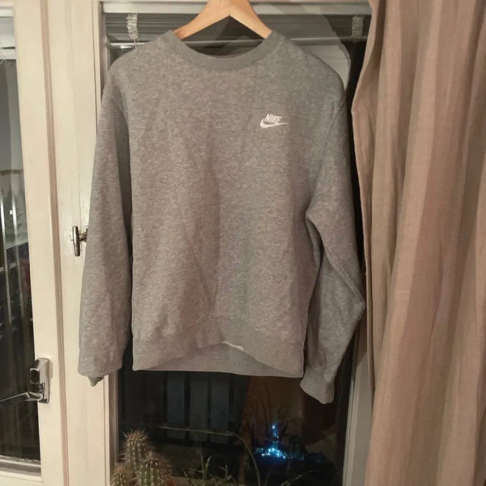 Säljer en grå sweatshirt från Nike i storlek XS. Tröjan är tillverkad av 80% bomull och 20% polyester, vilket gör den både bekväm och hållbar. Den har långa ärmar och en klassisk rund halsringning. Perfekt för höst och vår! Tröjan är i ett mycket bra skick förutom en söm som har gått upp och sytts igen på baksidan, den syns på sista bilden men märks inte när tröjan är på!. Tröjor & Koftor.