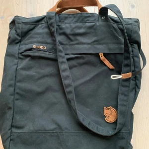 Fjällräven Totepack NO. 1 Unisex - Axelväska - Smidig väska i kraftig vaxad väv som kan bäras både på axeln, i handen och på ryggen. Dragkedja i öppningen och säkerhetsficka