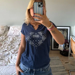 Mörkblå t-shirt från Levi's💙 - Säljer en snygg mörkblå t-shirt från Levi's med ett coolt paisleymönster i form av ett hjärta på framsidan. T-shirten är kortärmad och har en normal passform💙