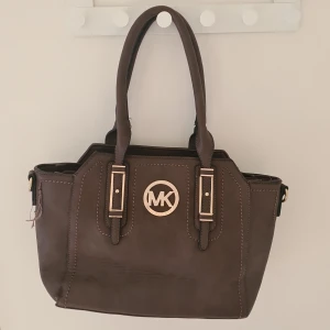 As snygg michael kors handväska - Perfekt nu till höst då den är skitsnygg, brun med gulddetaljer och rymlig, den har ett mittenfack med dragkedja (jag la ner en bok så man skulle se) och nigra små fack. Osäker på om den är äkta. Den har legat nerpackad en stund. En söm har gått upp