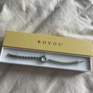 Silverfärgat armband med klocka från BOVOU - Snyggt och stilrent silverfärgat armband med en liten klocka från BOVOU. Bandet kan man justera och göra längre (se sista bilden) men spännet är lite löst och går lätt upp så det kan behöva lagas eller bytas ut. Oanvänd och nypris ca 1200❤️
