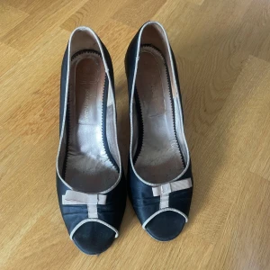 Klackskor  - Svarta klackskor med en beige rosett, storlek 39/40 - Köparen står för frakten - Inga returer - Betalning via köp direkt 