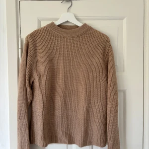 Stickad tröja - Säljer en superfin beige stickad tröja från NA-KD i storlek XXS, men passar även mig som vanligtvis har XS. Perfekt för höst och vinter med sin mysiga och varma känsla. Tröjan har långa ärmar och en ribbad krage. 