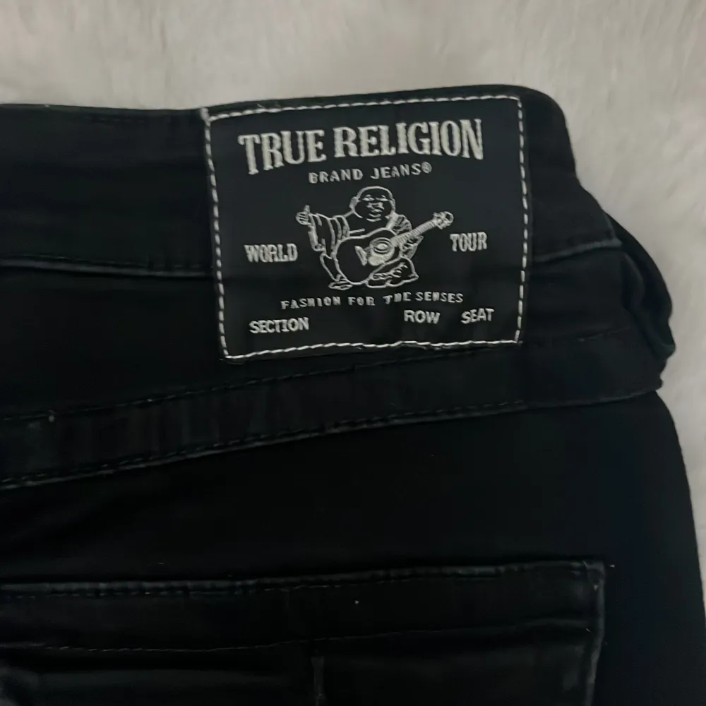 Säljer ett par svarta jeans från True Religion i modellen Joey. De har låg midja och är i bra skick men har ett litet hål längst nere, köpte dessa på raglady! Perfekta för en casual look🖤. Jeans & Byxor.