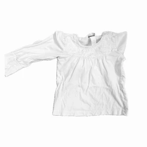 Vit blus med broderad detalj - Blus med långärmad design med broderade detaljer. Inga fläckar.