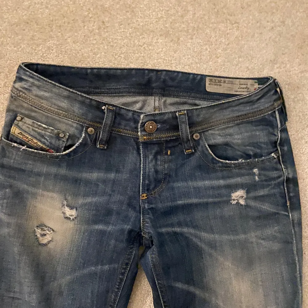 Säljer ett par as snygga Lågmidjade blå jeans från Diesel i modellen Lowky. De har en liten fläck vid knät men annars är dem i bra skick💕Bara att skriva om ni har några frågor🤩. Jeans & Byxor.