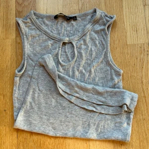 Grå ribbad ärmlös topp  - Supermjuk grå ribbad topp från Soul River i storlek S. Liten öppning vid halsen som ger en snygg detalj. Materialet är stretchigt, perfekt för både vardag och fest. 🩶 