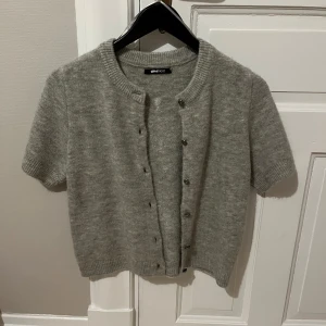 Grå kofta från Gina Tricot  - Säljer en superfin grå kofta från Gina Tricot. Den är kortärmad och har knappar framtill. Perfekt för lager-på-lager under hösten eller våren. Materialet känns mjukt och skönt mot huden. Passar både till vardags och lite finare tillfällen. Den är liten i storleken🌸