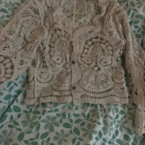 Beige virkad kofta - Säljer en superfin beige virkad kofta med unikt mönster. Perfekt för vår och sommar, den är både luftig och stilren. Koftan har långa ärmar och knappar framtill. Passar perfekt över en enkel topp för en bohemisk look. 🧶✨ Helt oanvänd