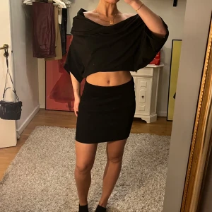 Svart kjol med dragkedja - Snygg svart kortkjol med en framträdande guldfärgad dragkedja baktill. Perfekt för både vardag och fest! Kjolen har en tight passform som framhäver figuren. Materialet ser ut att vara mjukt och bekvämt, vilket gör den idealisk för både höst och vår.