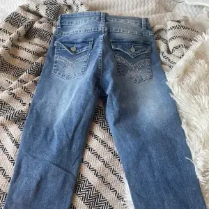 Snygga blå jeans i bra skick med broderade detaljer på bakfickorna. De har en klassisk bootcut-stil och är perfekta för både vardag och fest. Kontakta för mått💗