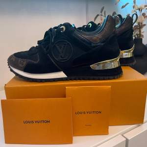 Säljer ett par snygga svarta sneakers från Louis Vuitton i mycket bra skick. Skorna har en elegant design med gulddetaljer på hälen och LV-logga på sidan. De är gjorda i en kombination av skinn och mocka med snörning framtill. Perfekta för både vardag och fest. Har lossnat lite guld i ena hälen men inget kan märker. Storlek 36 men känns som 37. Kvitto finns. 