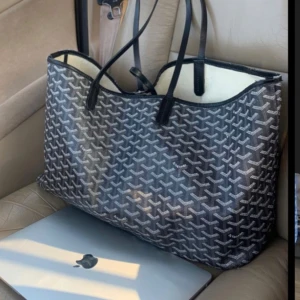  shoppingväska - Snygg och rymlig shoppingväska i blå och vitt med ett coolt geometriskt mönster. Perfekt för att bära med sig allt man behöver under dagen. Väskan har två långa handtag som gör den enkel att bära över axeln. Passar perfekt för både vardag och shoppingrundor.