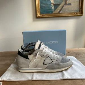 PHILIPPE MODEL SKOR - Säljer ett par snygga sneakers från Philippe Model. De har en stilren design med vita och grå detaljer samt en bekväm sula. Perfekta för både vardag och fest! Skorna är i bra skick och kommer med originalkartong. Hör av er vid funderingar!