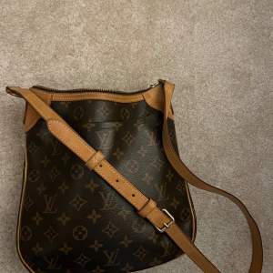 Louis Vuitton axelremsväska . Justerbar axelrem och dragkedja upptill. Insidan är rymlig med två fickor  för småsaker och en stor ficka på utsidan.Perfekt för både vardag och fest! Bred 27 cm Höjd 24 cm Djup 5 cm.