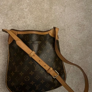 Louis Vuitton Odeon PM - Louis Vuitton axelremsväska . Justerbar axelrem och dragkedja upptill. Insidan är rymlig med två fickor  för småsaker och en stor ficka på utsidan.Perfekt för både vardag och fest! Bred 27 cm Höjd 24 cm Djup 5 cm.