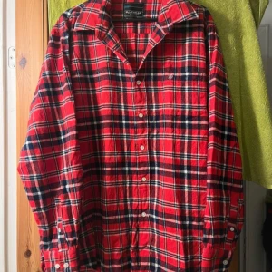 Röd rutig skjorta från Bluewear - Säljer en snygg röd rutig skjorta från Bluewear i storlek XXL. Skjortan har långa ärmar och knappar framtill. Perfekt för höst och vinter med sitt klassiska rutmönster i rött, svart och vitt. Passar både till vardags och festliga tillfällen. 🖤