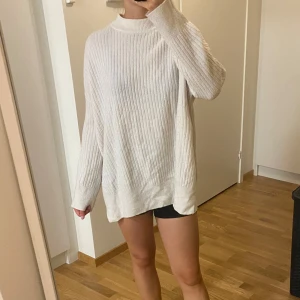 Vit ribbad stickad tröja - Mysig vit stickad tröja i oversized passform. Perfekt för kyliga dagar med sin ribbade struktur och långa ärmar. Enkel och stilren design som passar till allt. Perfekt för höst och vinter!